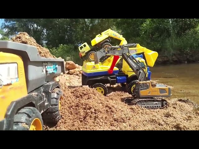 The excavator carry sand,tows the truck.The excavator goes to stream to scoop sand onto dump truck.