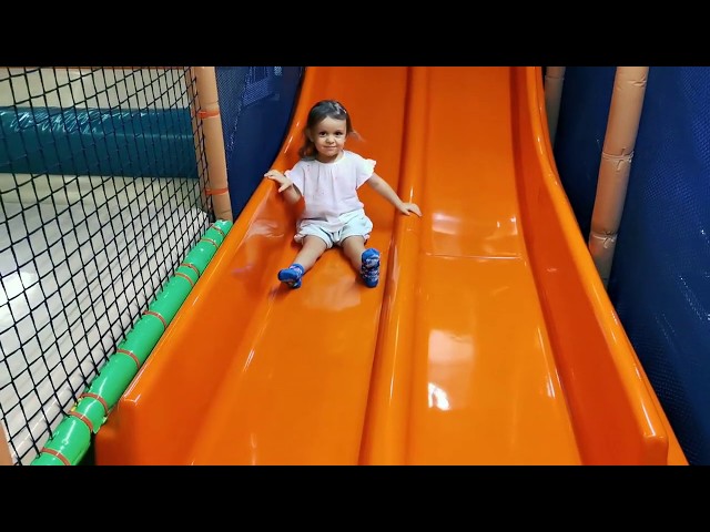 Little Mia on kids playground playing with magic flying balls and on slide. Kids entertainment